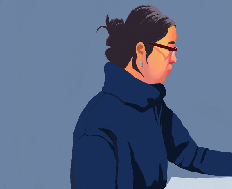 Asian woman with glasses, hair put up in bun, and turtleneck with arm resting on desk.